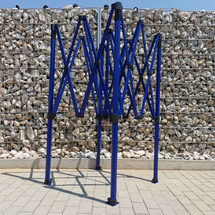 Laiendatud, kuid mitte tulistatud sinine konstruktsioon (raam) lõikeparti telgist, seisev sillutisel kivikeste taustal (aiaga).